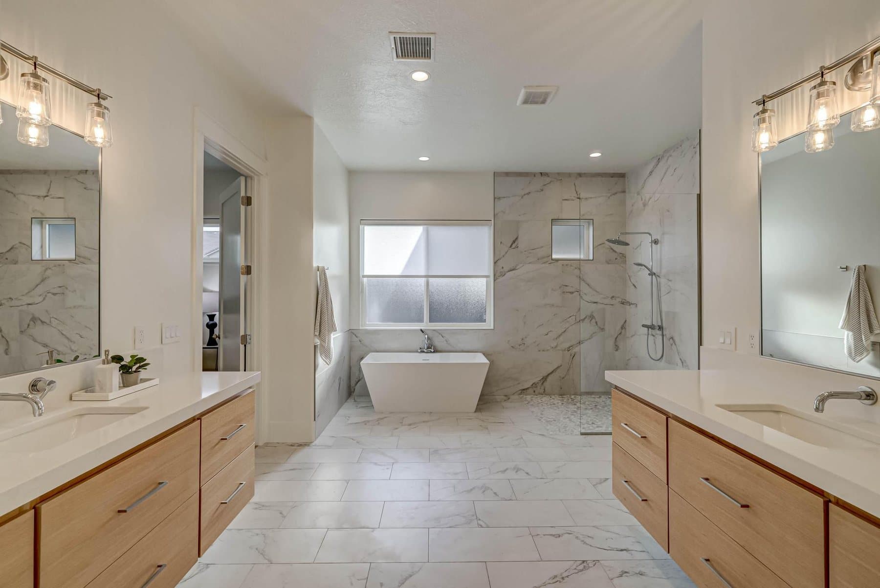 The primary bath — double vanities, freestanding tub and tiled walk-in shower