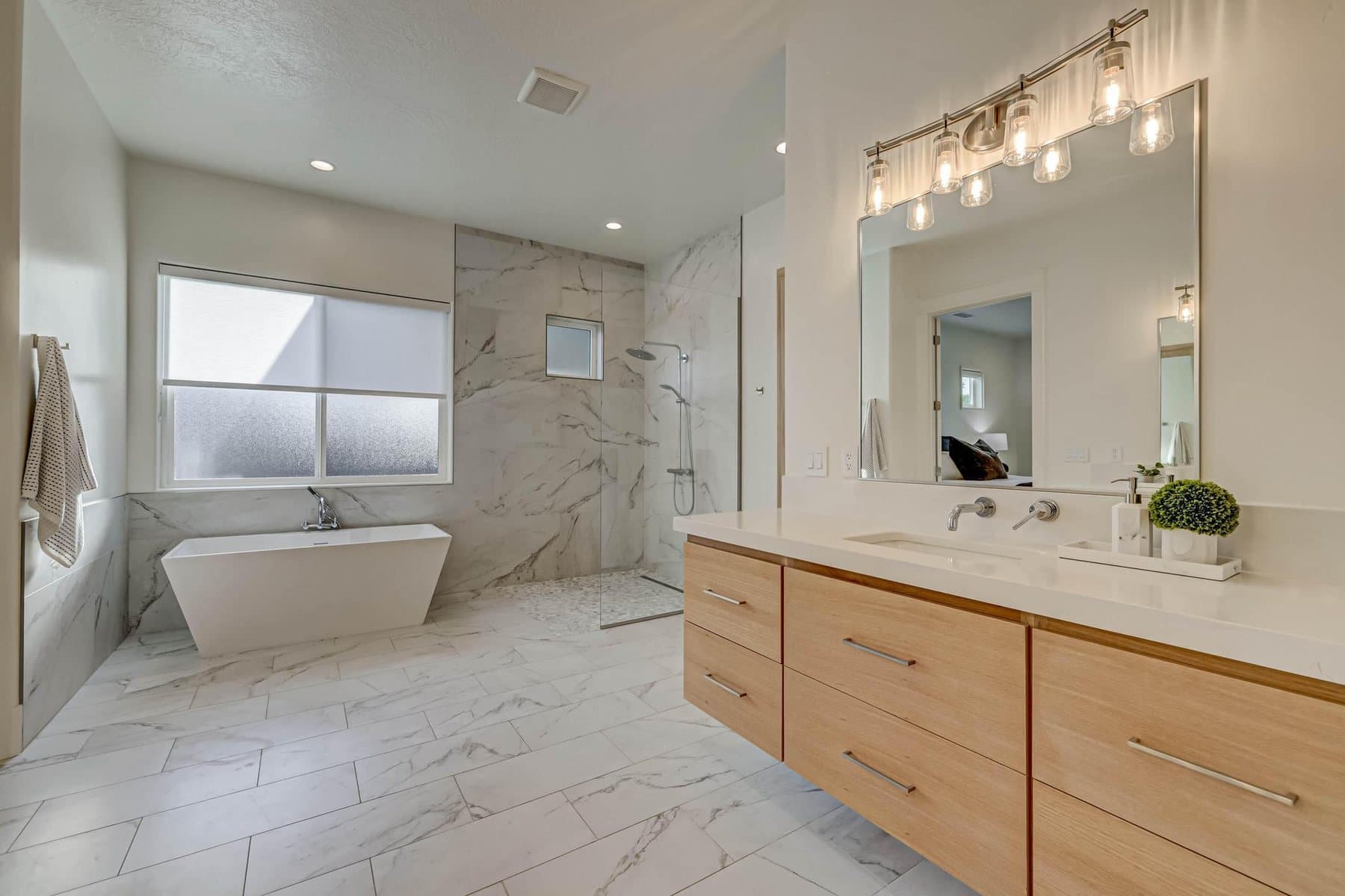 The primary bath — double vanities, freestanding tub and tiled walk-in shower