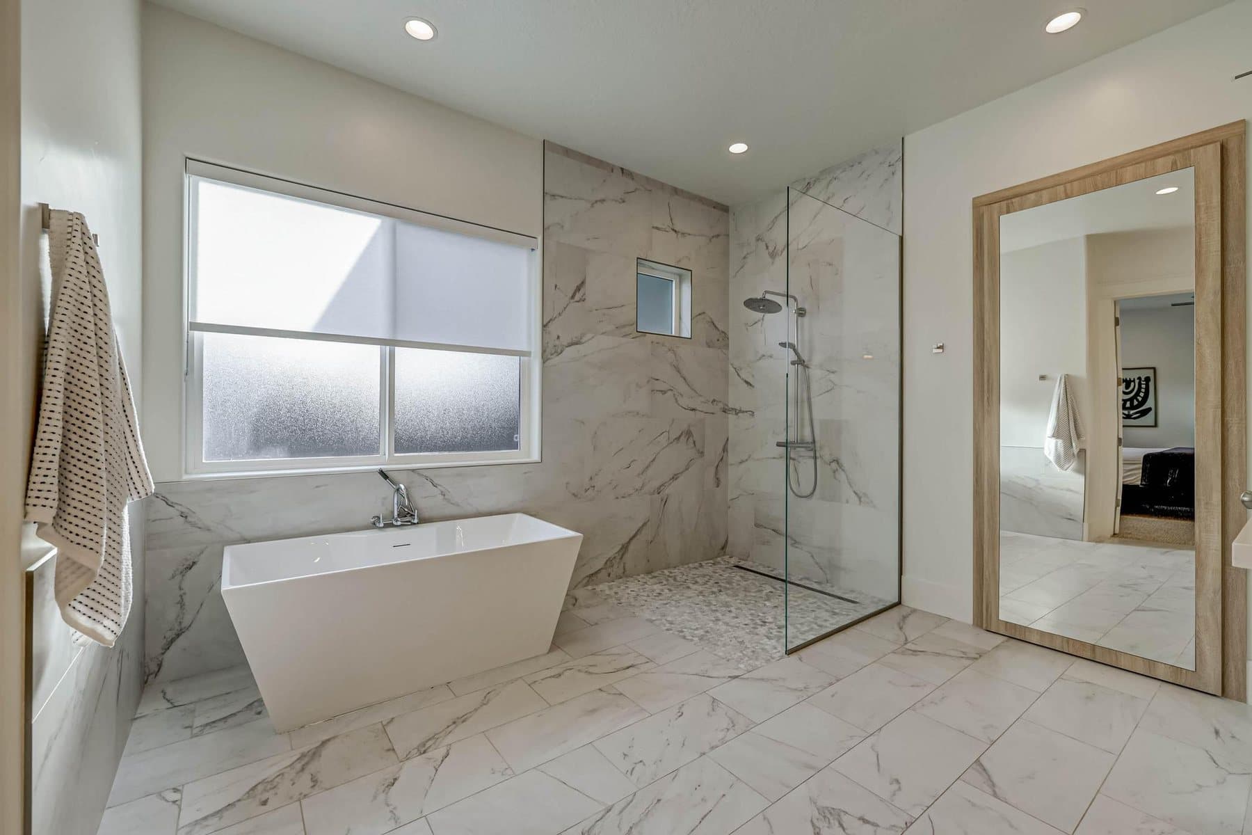 The primary bath — double vanities, freestanding tub and tiled walk-in shower